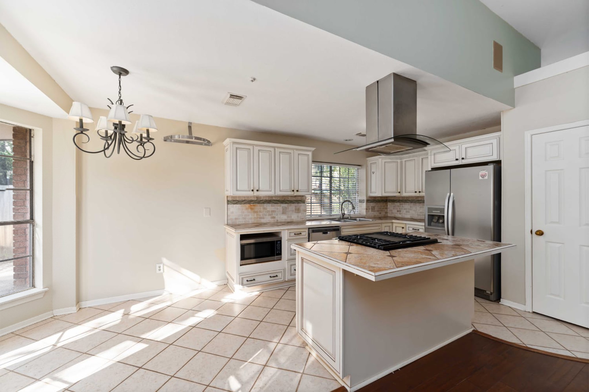 19927 Teller Boulevard Spring, TX 77388 - Photo 12 of 42 White cabinetry is paired with tile countertops and a neutral stone backsplash, featuring a built-in microwave and dishwasher.