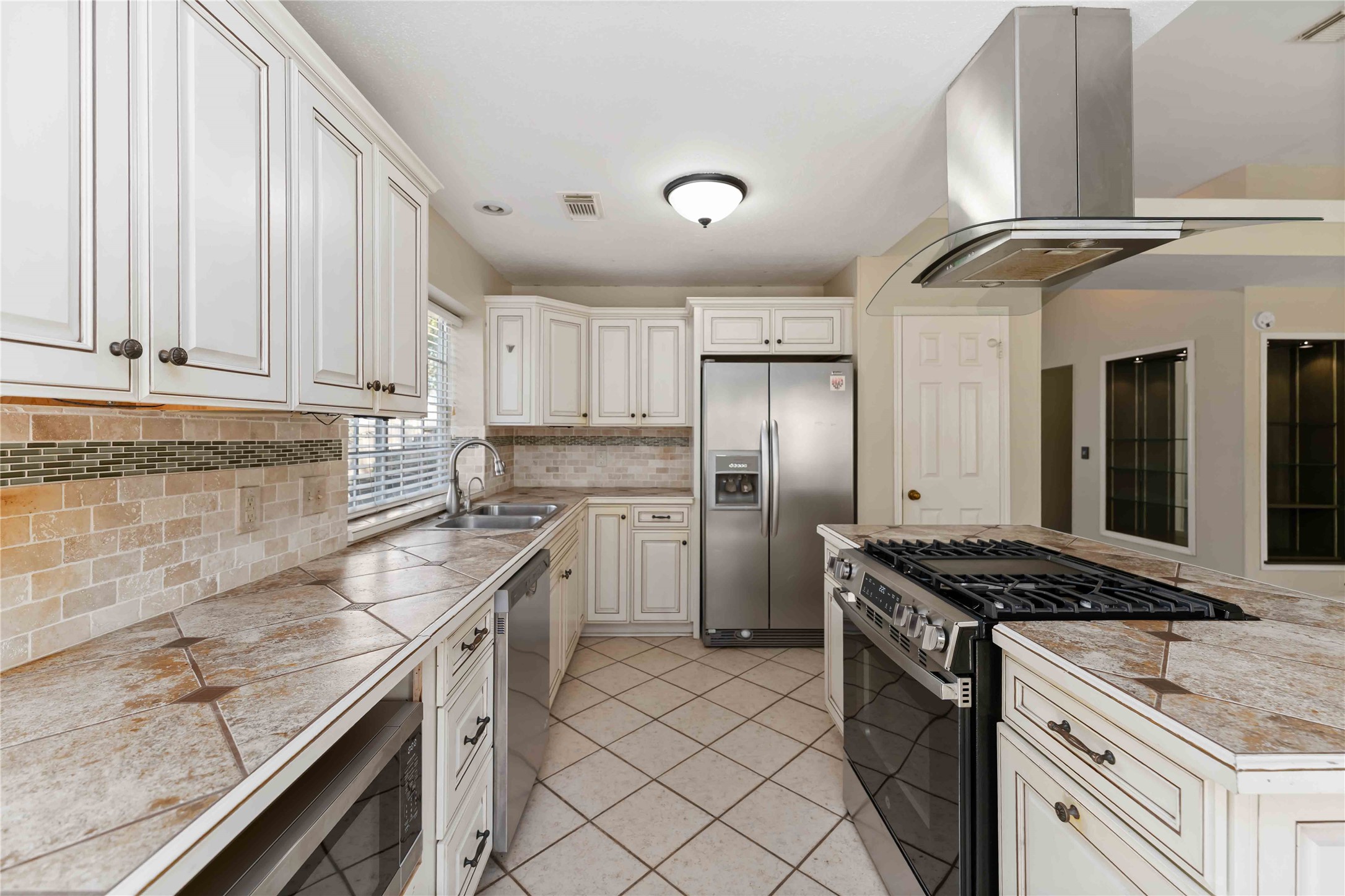 19927 Teller Boulevard Spring, TX 77388 - Photo 13 of 42 This view highlights the double stainless steel sink, side-by-side refrigerator, and the transition from tile to wood-look flooring.