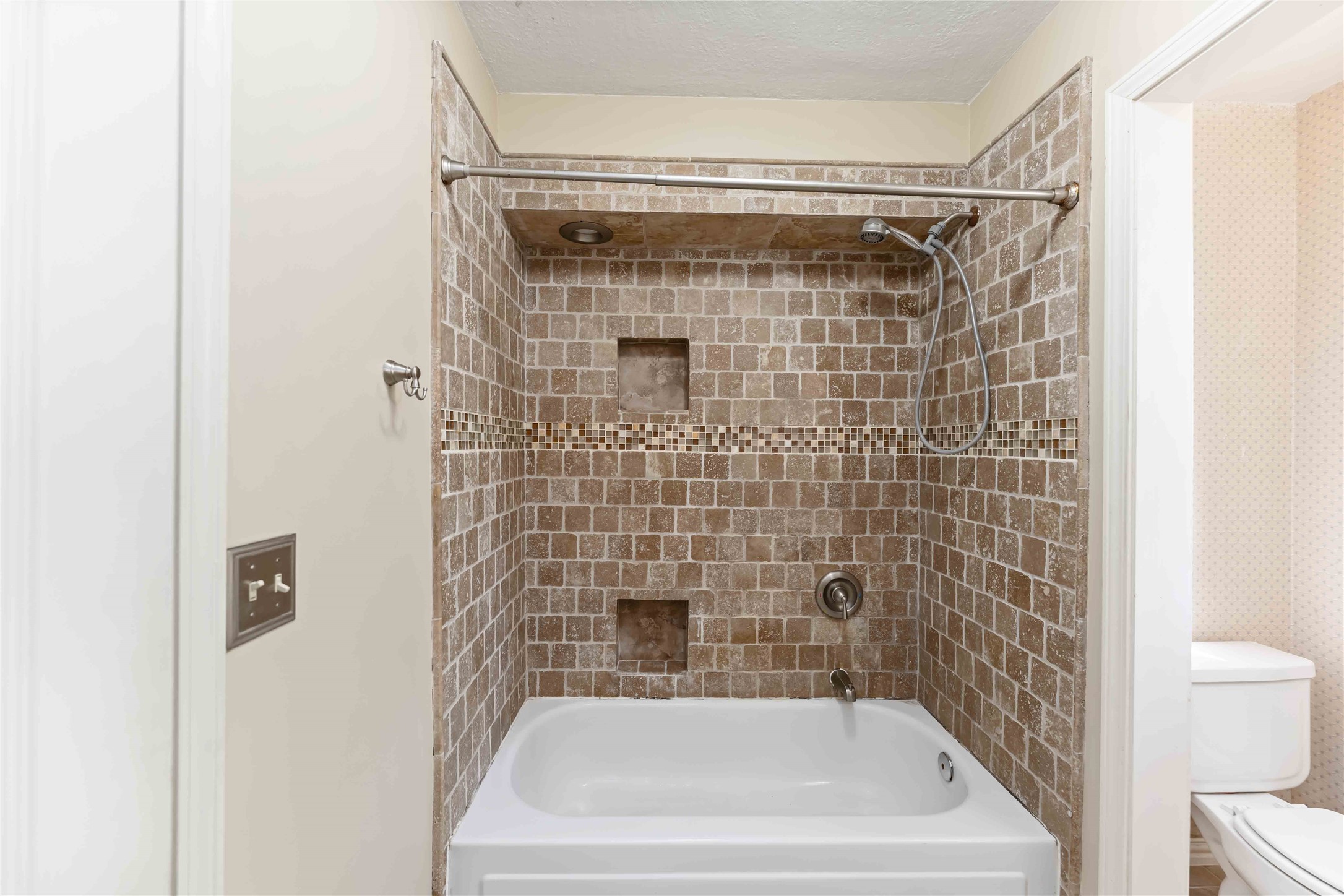 19927 Teller Boulevard Spring, TX 77388 - Photo 30 of 42 This full bathroom features a shower-tub combination with floor-to-ceiling earth-tone tiles and built-in recessed shelving.