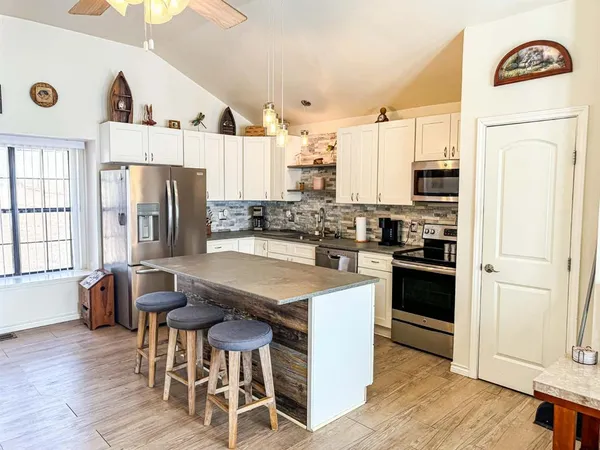 a kitchen with stainless steel appliances granite countertop a refrigerator a stove a sink dishwasher and white cabinets with wooden floor