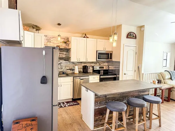 a kitchen with stainless steel appliances a refrigerator a stove a sink dishwasher and white cabinets with wooden floor