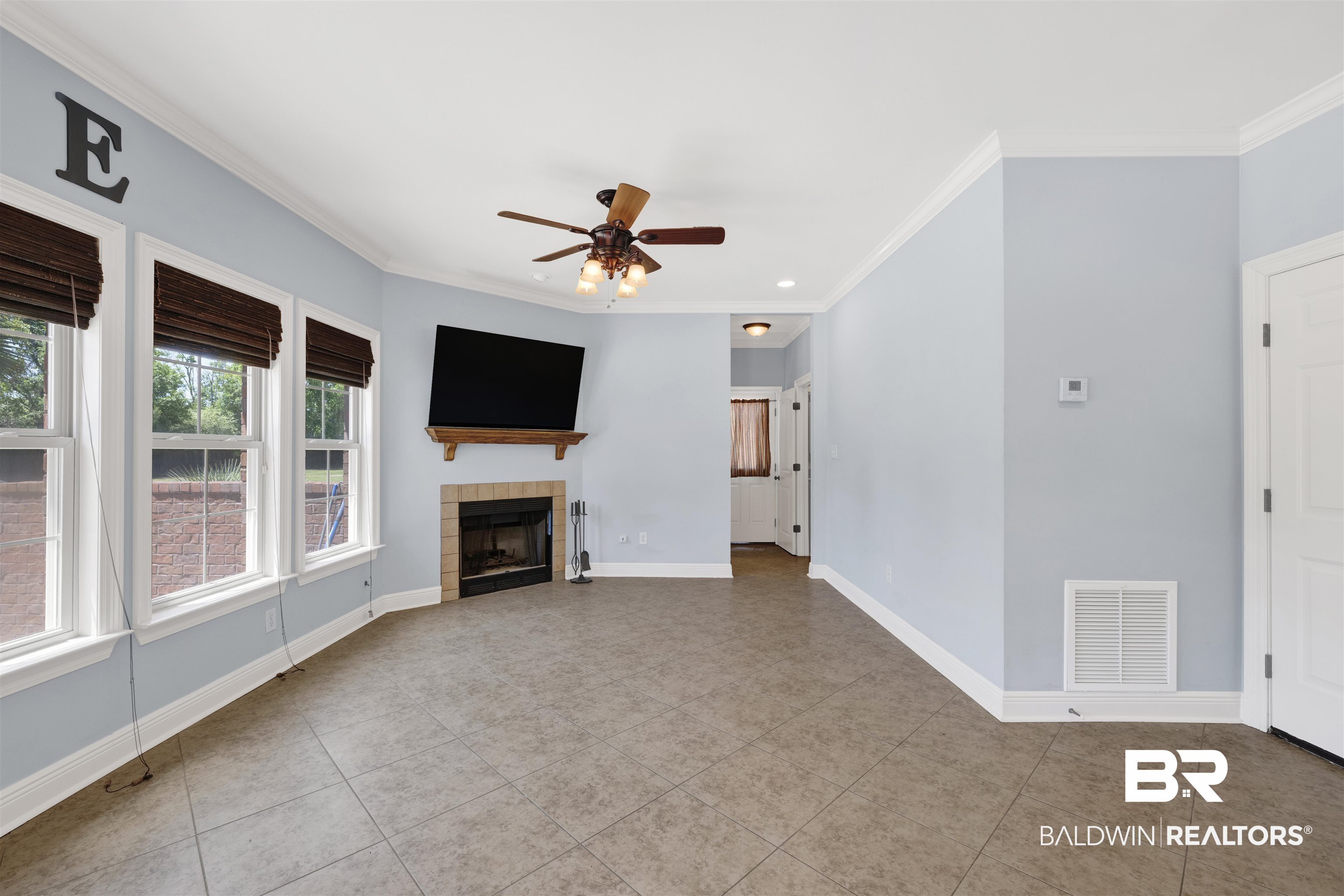12944 Anna's Way Stapleton, AL 36578 - Photo 38 of 64 Living area featuring a corner fireplace with brick surround and wood mantel, diagonal-set tile flooring, and multiple windows with dark-toned shades