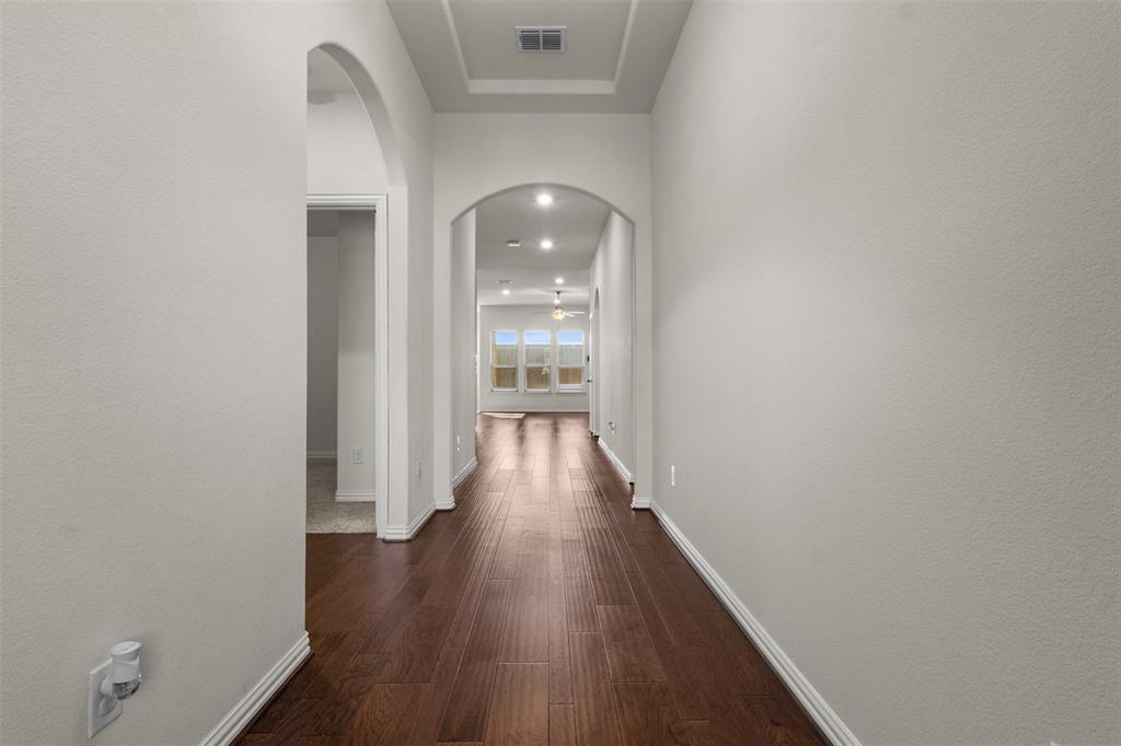 1740 Rio Costilla Road Fort Worth, TX 76131 - Photo 3 of 40 Archways define the hallway with wood-finish flooring, recessed lighting, and a tray ceiling detail