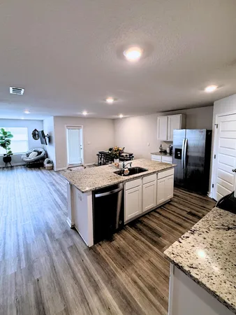 a kitchen with stainless steel appliances granite countertop a stove a sink dishwasher a microwave oven and a refrigerator with wooden floor