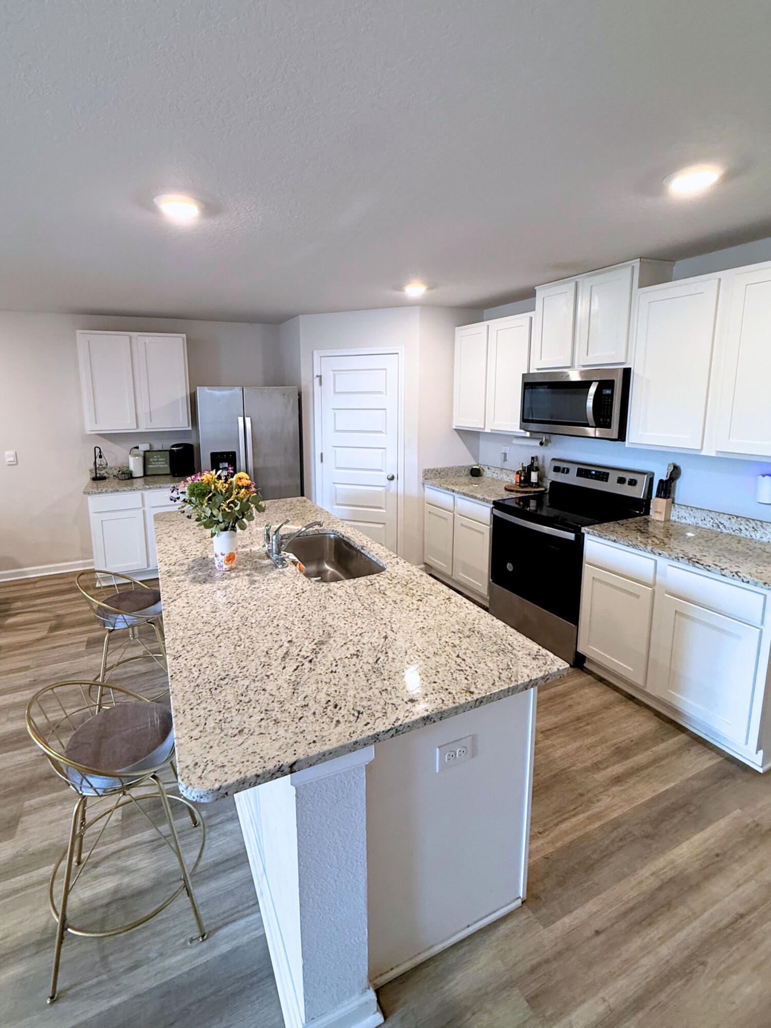809 Otto Loop Crestview, FL 32539 - Photo 6 of 26 a kitchen with stainless steel appliances granite countertop a stove a sink dishwasher a microwave oven and a refrigerator with wooden floor