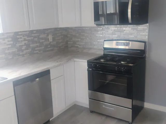 a kitchen with granite countertop white cabinets and stainless steel appliances