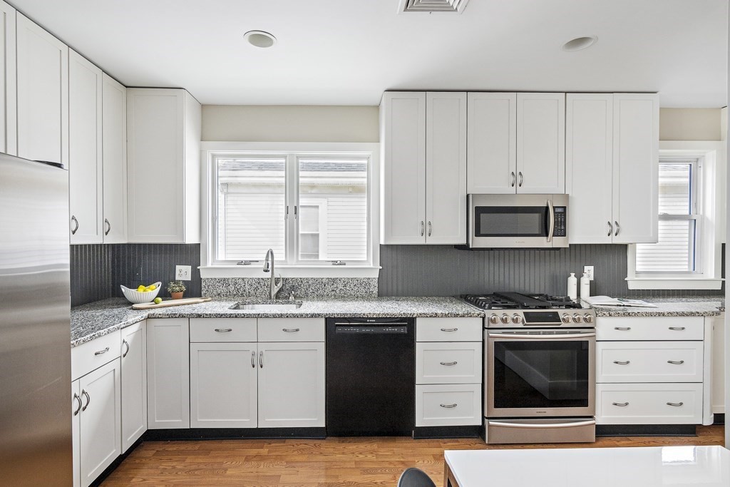 22 Wellington Road Medford, MA 02155 - Photo 3 of 16 a kitchen with white cabinets sink and stainless steel appliances