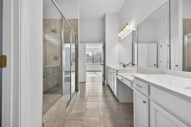 a large bathroom with a granite countertop double vanity sink a mirror a shower and a bathtub