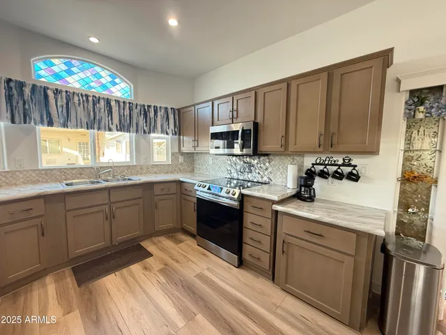 a kitchen with granite countertop a sink cabinets stainless steel appliances and a window