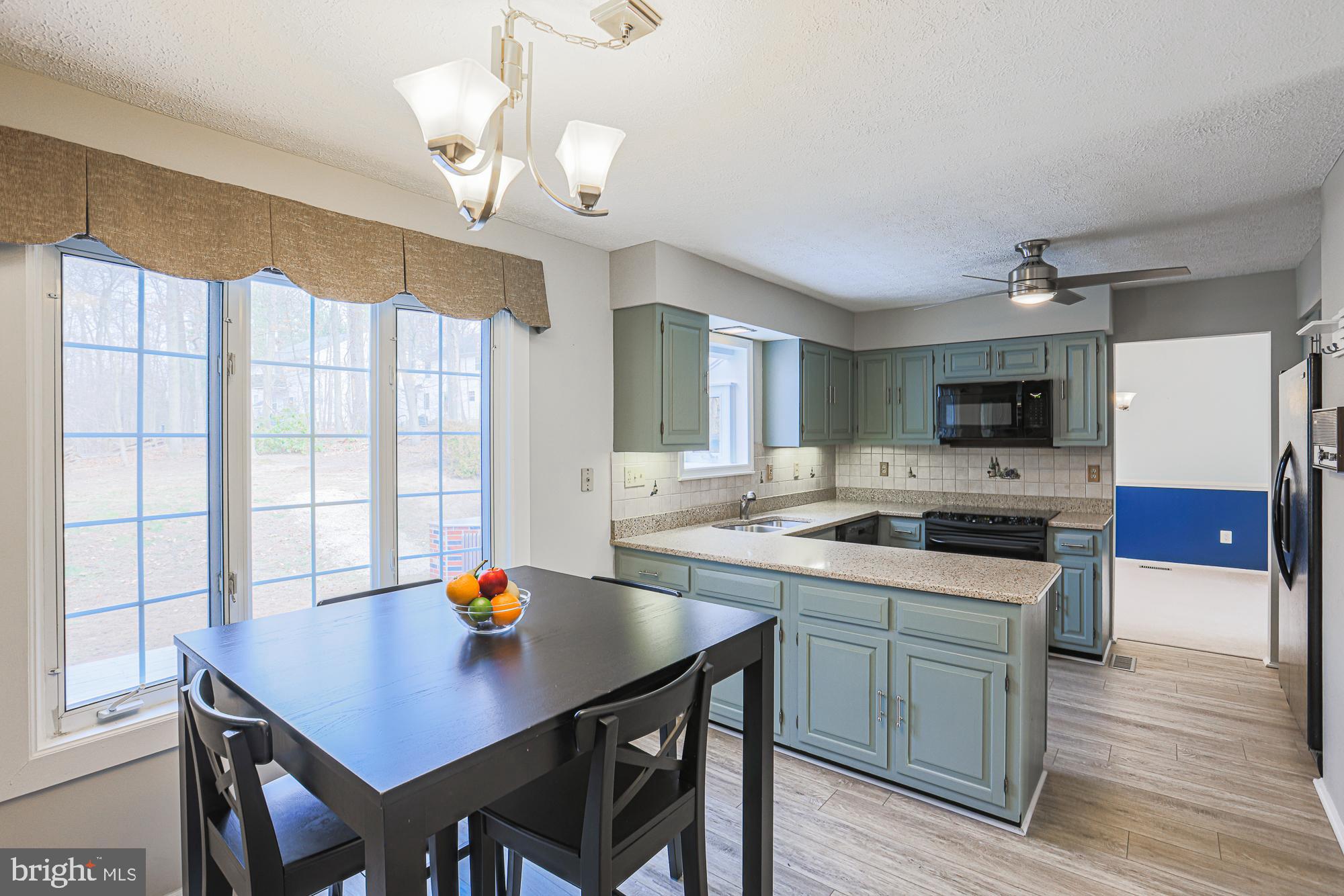 4402 Macworth Place Nottingham, MD 21236 - Photo 12 of 36 a kitchen with a stove a sink dishwasher a dining table and chairs with wooden floor
