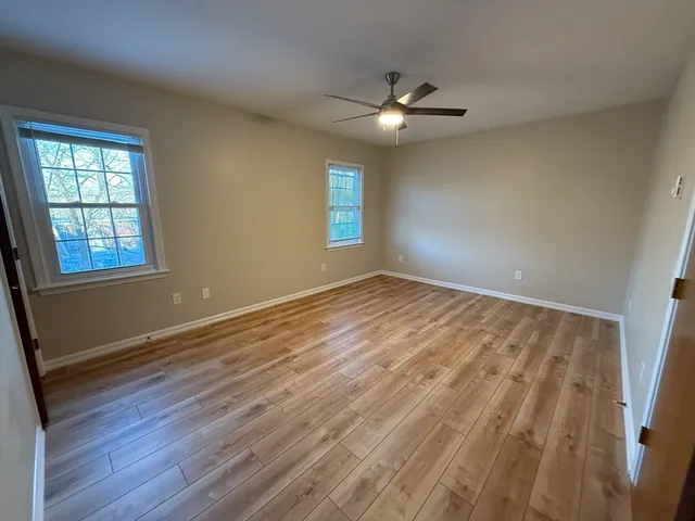 a view of an empty room with window and wooden floor