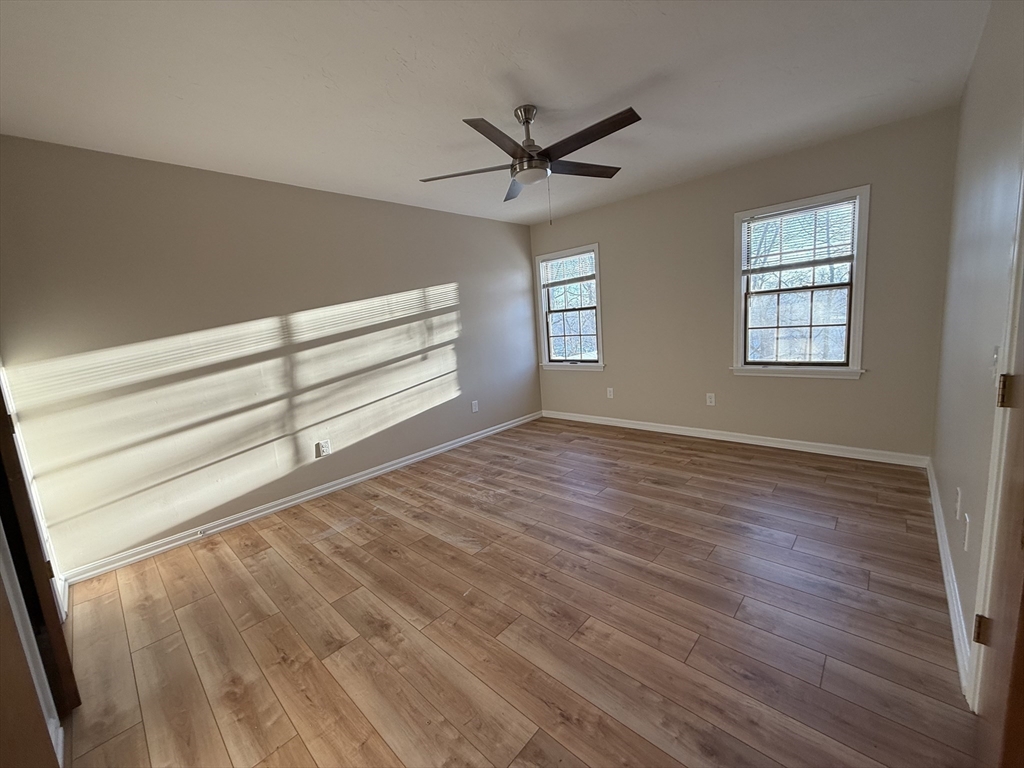 230 Beacon Street, Unit 3 Clinton, MA 01510 - Photo 9 of 13 a view of a livingroom with wooden floor a ceiling fan and windows