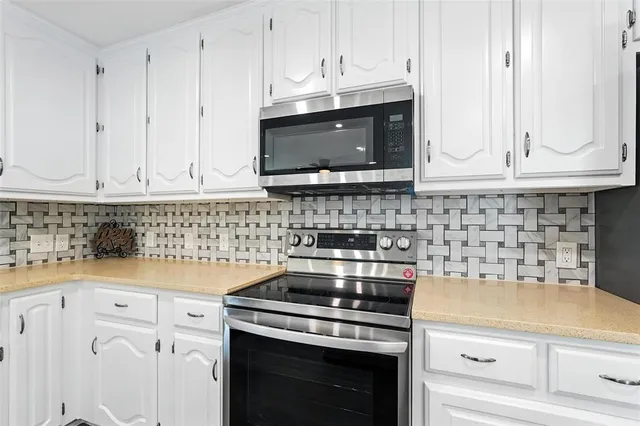 a kitchen with a sink and dishwasher with white cabinets