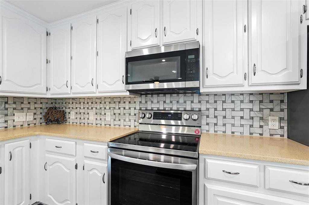 1402 Country Lane Allen, TX 75002 - Photo 14 of 39 Kitchen featuring appliances with stainless steel finishes, white cabinets, decorative backsplash, and light stone counters