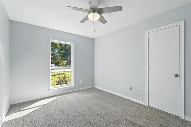 an empty room with windows and ceiling fan