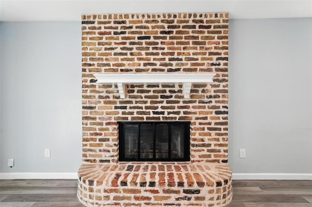 1402 Country Lane Allen, TX 75002 - Photo 9 of 39 Detailed view of wood finished floors and a brick fireplace