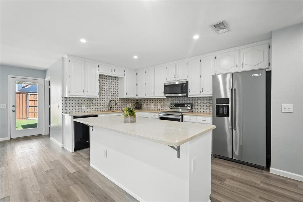 1402 Country Lane Allen, TX 75002 - Photo 10 of 39 Kitchen featuring appliances with stainless steel finishes, white cabinets, a center island, decorative backsplash, and recessed lighting