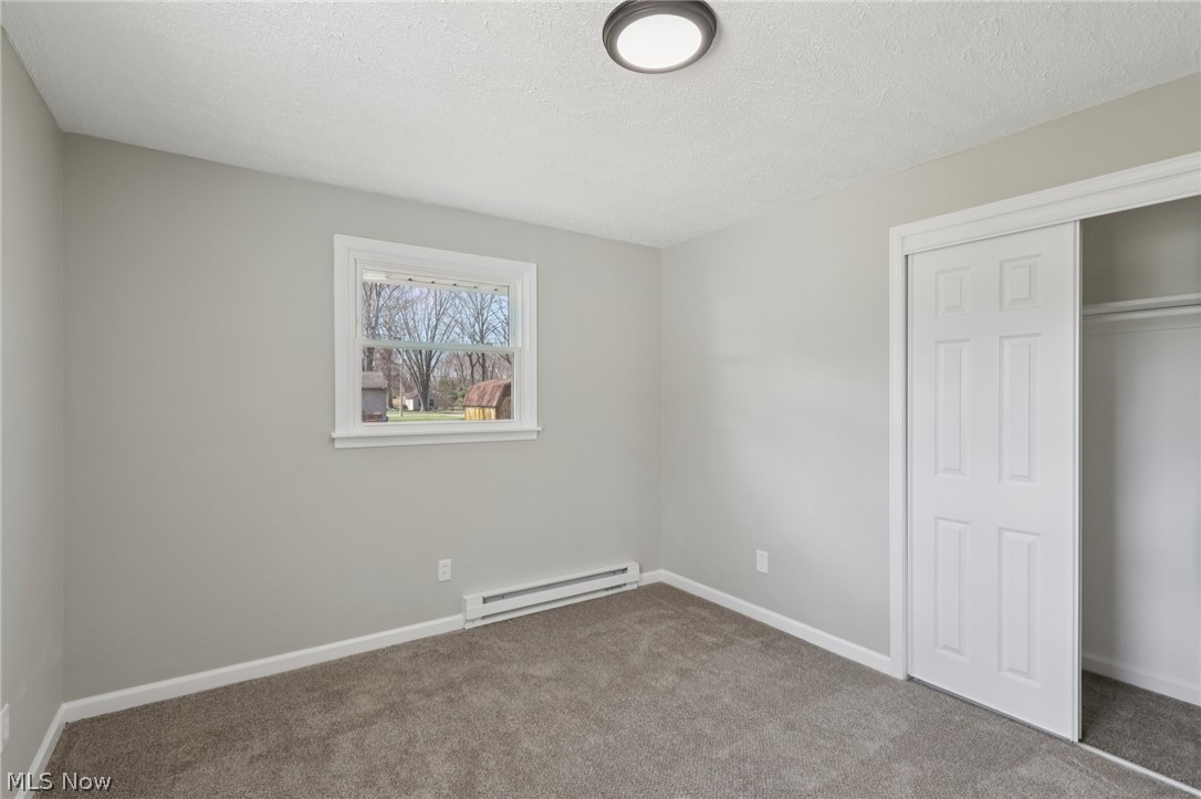 7412 Hopkins Road Mentor, OH 44060 - Photo 23 of 36 Unfurnished bedroom featuring a baseboard radiator, carpet flooring, a closet, and a textured ceiling
