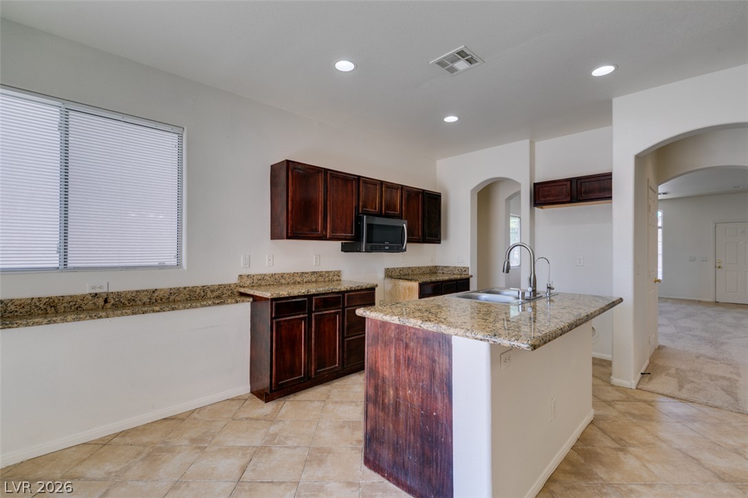 5150 Riverside Run Court North Las Vegas, NV 89081 - Photo 30 of 50 A functional kitchen island anchors this well-appointed space, featuring durable granite counters and warm wood cabinetry.