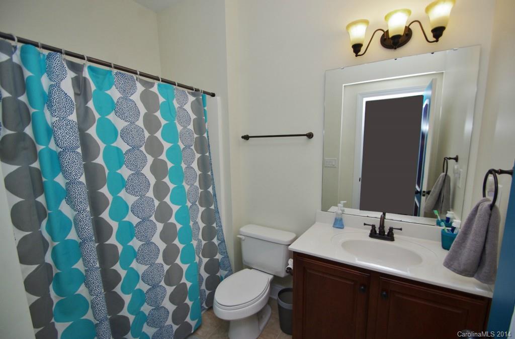 1010 Hamil Ridge Drive, Unit 929 Waxhaw, NC 28173 - Photo 19 of 24 a bathroom with a sink a toilet a mirror and shower curtain