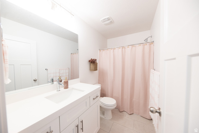 1404 East Rustic Wood Court Sandy, UT 84092 - Photo 24 of 33 Bathroom featuring a single vanity with an integrated sink, white cabinetry with brushed nickel hardware, a rectangular mirror, and light-toned floor tiles