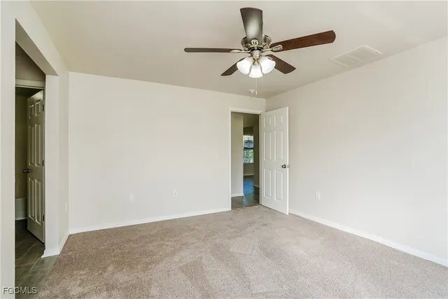 a view of an empty room and chandelier fan