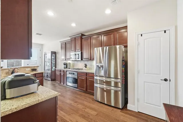 a kitchen with kitchen island granite countertop stainless steel appliances wooden floor and sink