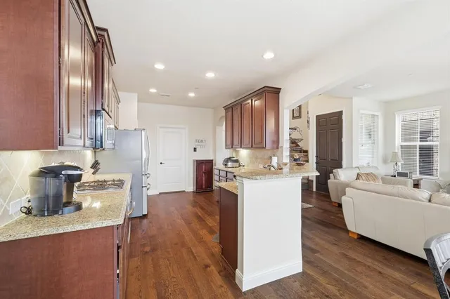 a kitchen with a sink dishwasher a stove and white cabinets with wooden floor