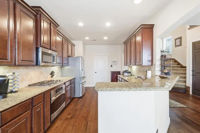 a kitchen with stainless steel appliances granite countertop a sink stove and cabinets
