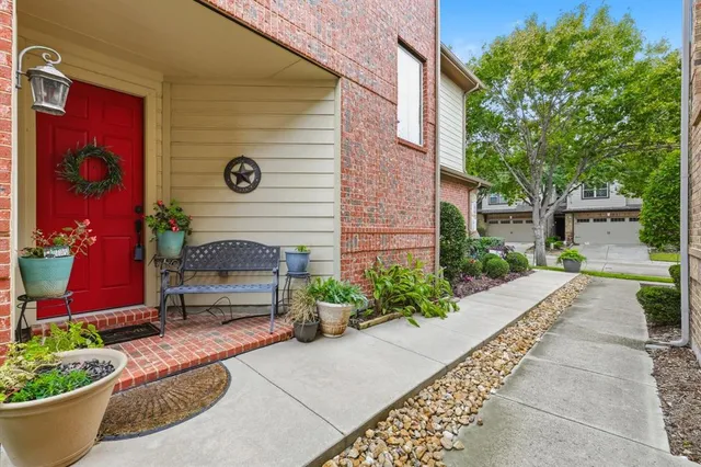 a view of a house with potted plants and a bench