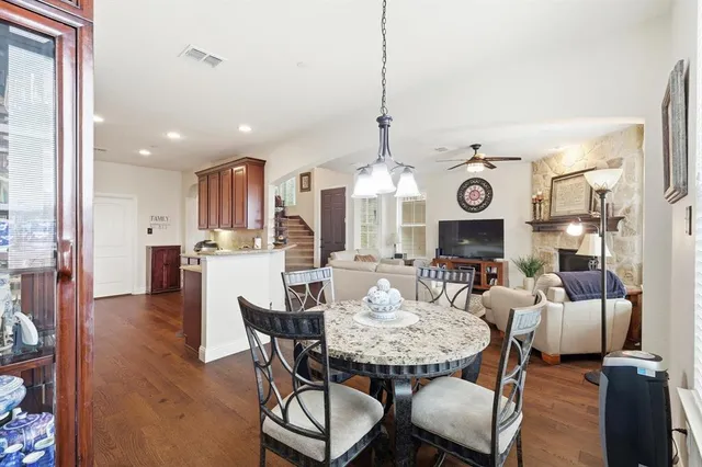 a view of a dining room and livingroom with furniture wooden floor a rug a fireplace and a chandelier