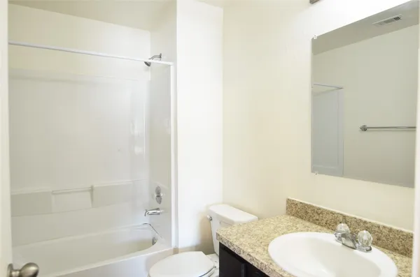 a bathroom with a granite countertop sink toilet and shower