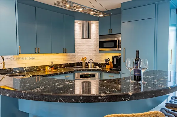 a kitchen with granite countertop a stove top oven a sink a counter space and cabinets