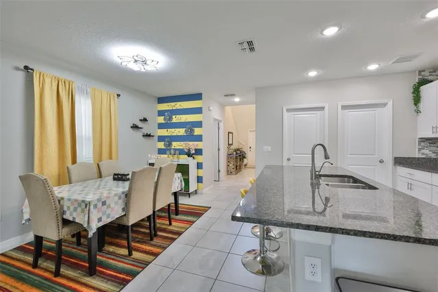 a dining hall with stainless steel appliances granite countertop a sink a table and chairs