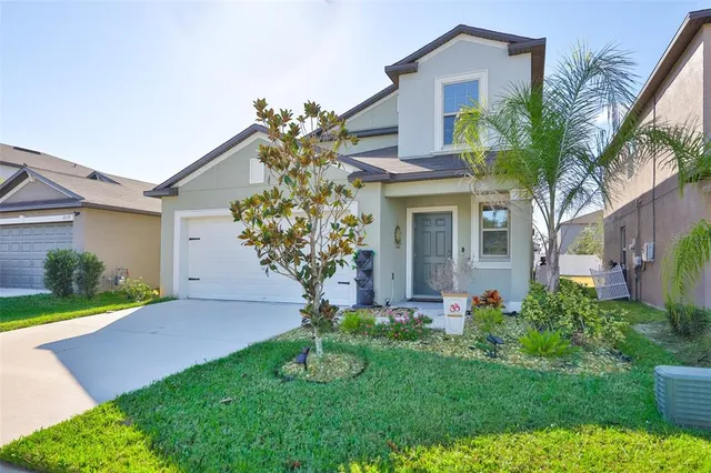 a front view of a house with a yard and potted plants