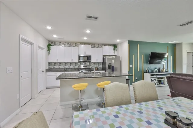 a living room with stainless steel appliances furniture a rug and a view of kitchen