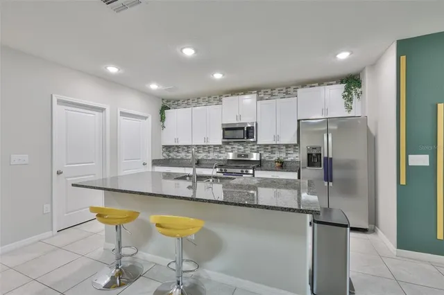 a kitchen with stainless steel appliances granite countertop a refrigerator and a stove top oven