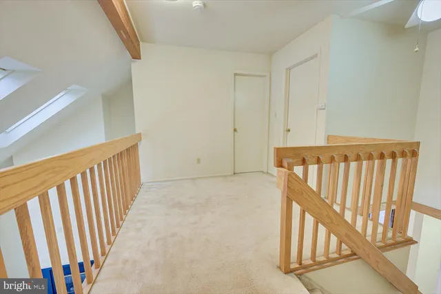 an empty room with chandelier fan and windows