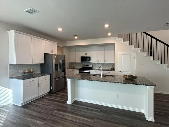 a kitchen with stainless steel appliances granite countertop a stove a sink and a refrigerator