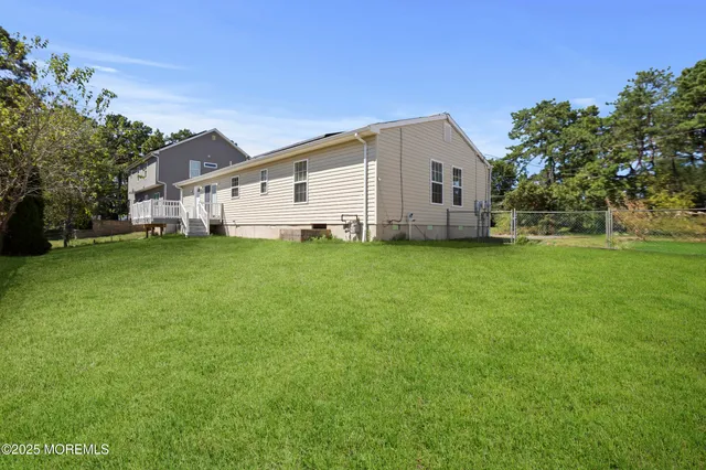 a house that is sitting in the grass with large trees and plants