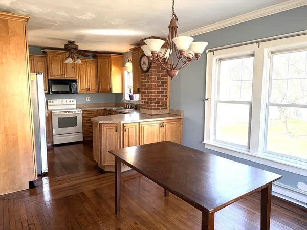 a kitchen with stainless steel appliances granite countertop a stove a sink dishwasher a refrigerator and a dining table with wooden floor