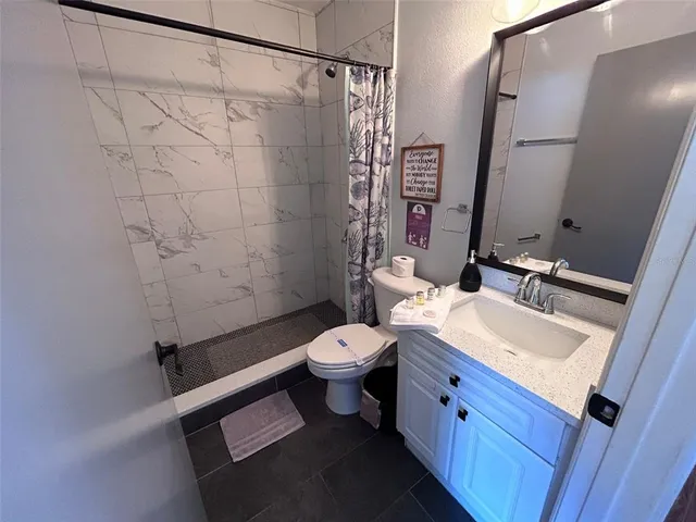 a bathroom with a granite countertop sink toilet and shower