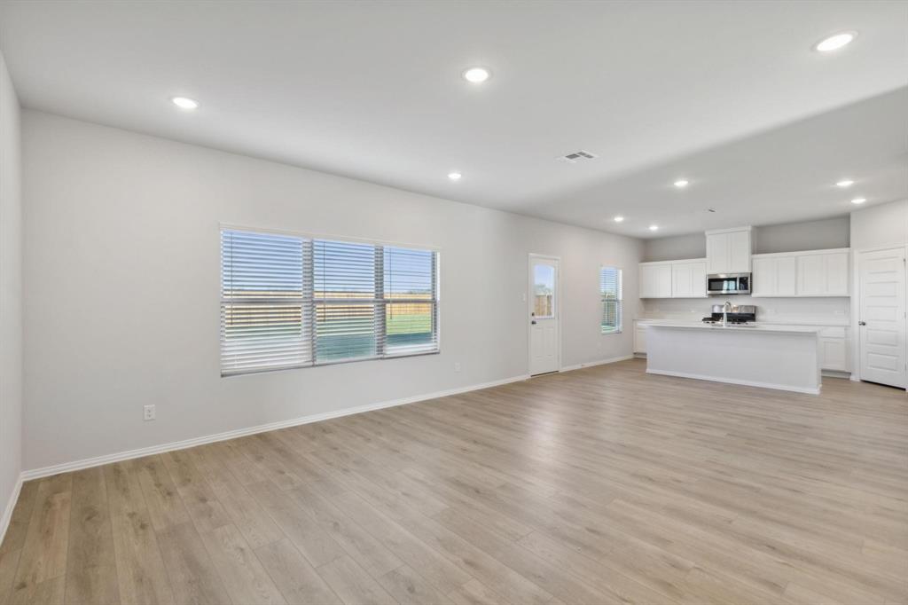 Unfurnished living room with light wood finished floors, recessed lighting, baseboards, and a sink