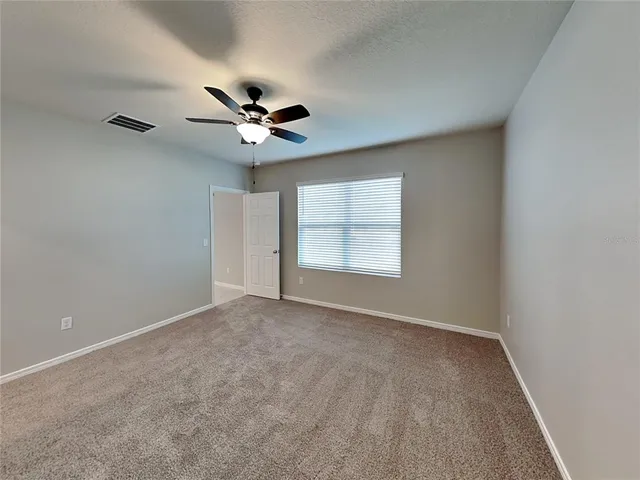 an empty room with windows and ceiling fan