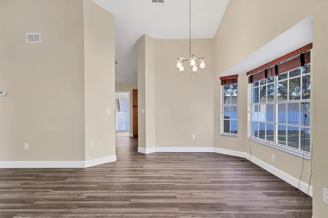 a view of a livingroom with wooden floor a chandelier and windows