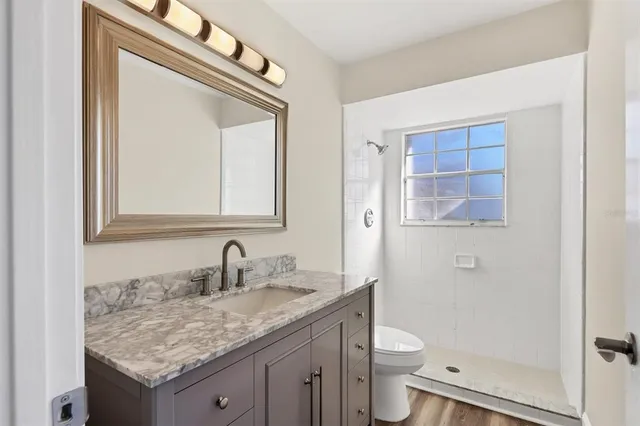 a bathroom with a granite countertop toilet sink and mirror