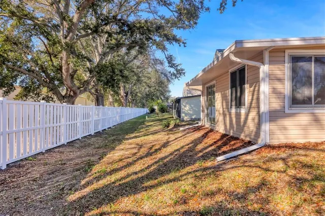 a view of backyard with wooden fence and large trees