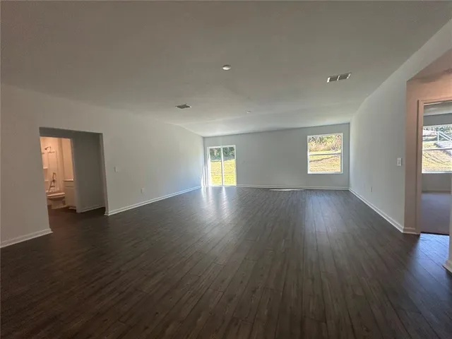 a view of an empty room with wooden floor and window