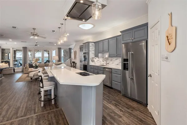 a kitchen with stainless steel appliances a refrigerator a sink dishwasher a stove and a dining table with wooden floor