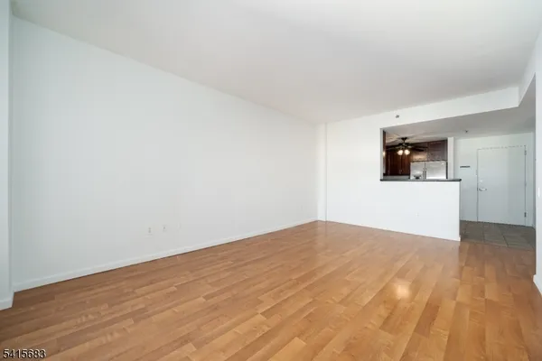 a view of empty room with wooden floor and ceiling fan